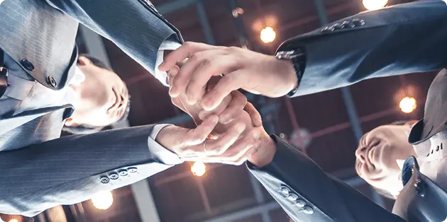 複数人で手を重ねて契約成立を祝う様子